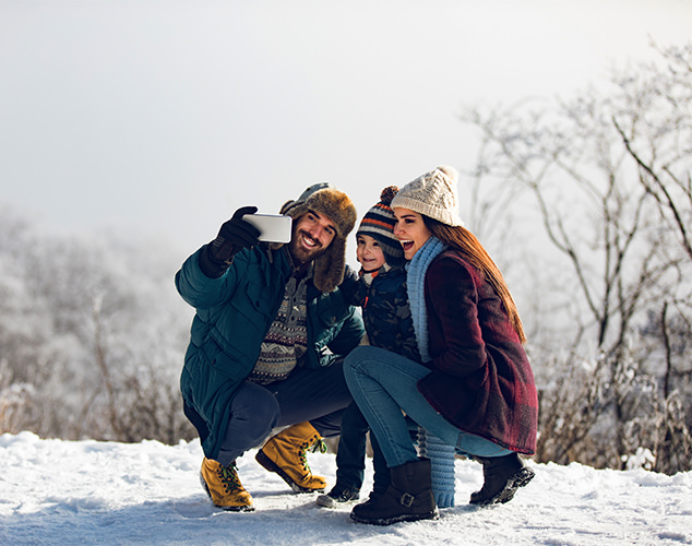 Parents and son taking selfie in snow